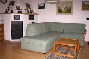 Uma sala de estar com um sofá verde, uma mesa de centro de madeira, uma lareira e várias decorações nas paredes.