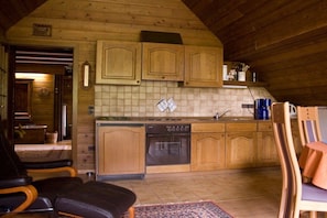 A cozy kitchen with wooden cabinets, a dishwasher, and a dining area with chairs. - Holiday apartment in Iggelbach with Wi-Fi (Iggelbach)