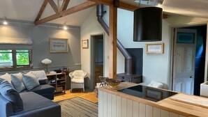 Una sala de estar acogedora con sofá, chimenea y zona de cocina con mostrador de madera.