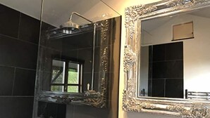 Un baño con ducha, lavamanos y dos espejos decorados.