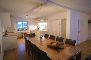 A modern kitchen with a wooden dining table, chairs, and a chandelier. - Holiday home in Steibis with swimming pool (Steibis)
