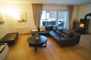 A living room with a sectional sofa, a round coffee table, a fireplace, and a window with curtains. - Holiday home in Steibis with swimming pool (Steibis)