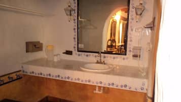 Un baño con un lavamanos blanco, un espejo con detalles florales y un perchero para toallas.
