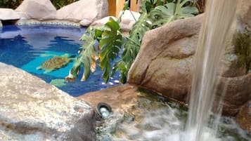Una piscina con cascada, rodeada de rocas y plantas.