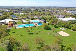 Vista aérea de um bairro residencial com piscina, toboágua e um amplo campo gramado.