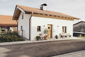 A single-story building with a tiled roof, a front door, and a bench outside. - high-quality with sauna (Ruhpolding)