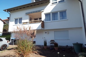 Ein zweistöckiges Wohngebäude mit Balkon, Garage und Auffahrt.
