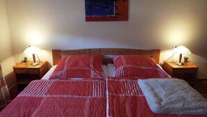 Un dormitorio con dos camas, cabecero de madera, lámparas de noche y un cuadro en la pared.
