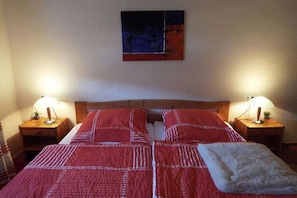 Ein Schlafzimmer mit zwei Betten, einem Holzkopfende, Nachttischlampen und einem Bild an der Wand.