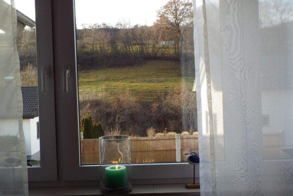 Una ventana con vista a un campo cubierto de hierba y una valla de madera.