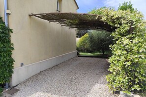 A covered outdoor area with a gravel floor, a pergola, and surrounding greenery. - Bastide des Grandes Terres gite Alpilles (MERINDOL)