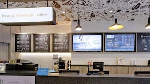A coffee shop interior with a menu board, digital screens, and a counter. - Hanting Hotel Shanghai Dapuqiao Ruijin Nan Road (Shanghai)