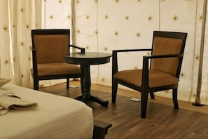 Ein Hotelzimmer mit zwei Sesseln, einem kleinen runden Tisch und einem Bett.