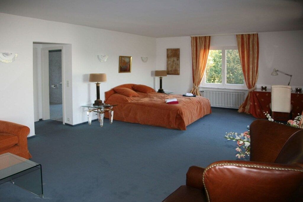 A hotel room with a bed, a desk, a chair, and a window with curtains.