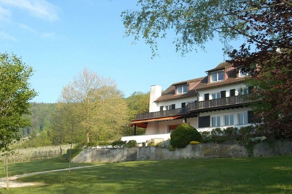 A large, two-story house with a balcony, surrounded by a well-maintained lawn and trees. - "Stutengarten Estate" (Öhningen)