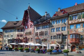 A historic European town square with traditional buildings, outdoor seating, and a cobblestone ground. - "Stutengarten Estate" (Öhningen)