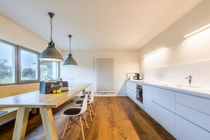 Eine moderne Küche mit einem Holztisch, zwei Pendelleuchten und einem weißen Heizkörper.