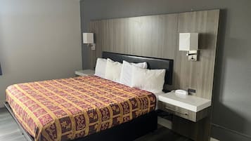 Una habitación de hotel con cama, mesitas de noche y lámparas de pared.