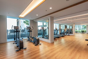 Una sala de gimnàstica amb cintes de córrer, el·líptiques i un paviment de fusta.