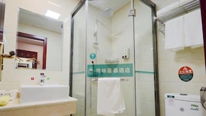 Une salle de bain d’hôtel avec une douche à parois de verre, un lavabo et des toilettes.