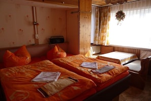 Ein Zimmer mit zwei Betten, einem Holzkopfende, einem Radio und einem Fenster mit Vorhängen.