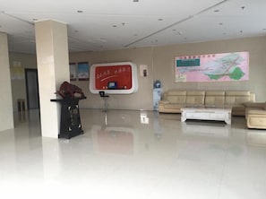 Um hall espaçoso com balcão de recepção, um mapa na parede e um sofá.