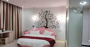 Quarto moderno com cama, mesa de cabeceira, cômoda e um mural de árvore na parede.