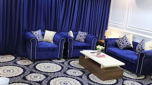 A room with two blue sofas, a white coffee table, and a patterned rug. - Lailaty Hotel Apart (Riyadh)