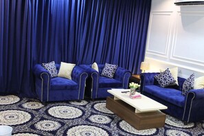 Een kamer met twee blauwe banken, een witte salontafel en een kamerbreed tapijt met een patroon.