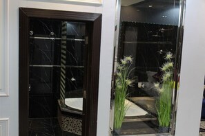 Een hotelentree met een donkerhouten deur, een ruit en een kleine potplant met witte bloemen.