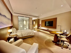 A modern hotel room with a bed, a desk, a chair, a TV, and a glass-enclosed shower. - Metropolo Wuhan Optics Valley Convention&exhibition Center Hotel (Wuhan)