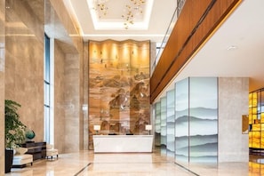 A modern lobby with a reception desk, a large mural, and a glass partition. - Metropolo Wuhan Optics Valley Convention&exhibition Center Hotel (Wuhan)