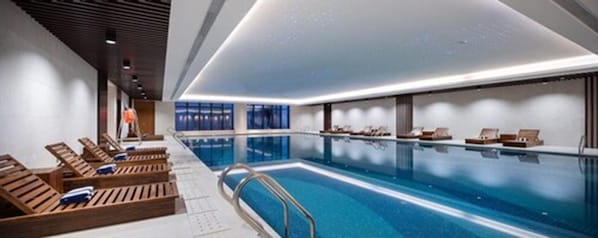An indoor swimming pool with wooden loungers and a clear blue pool. - Metropolo Wuhan Optics Valley Convention&exhibition Center Hotel (Wuhan)