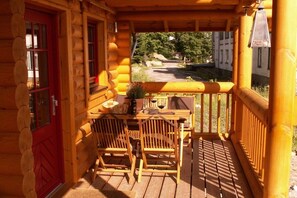 A wooden cabin with a porch, a table with chairs, and a red door. - Holiday home in Schierke with sauna (Schierke)