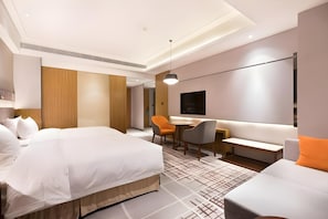 Una habitación de hotel moderna con una cama grande, un escritorio, un sofá y un televisor.