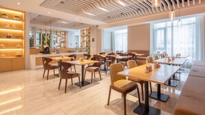 A modern dining area with multiple tables and chairs, a bar area, and a ceiling with a unique wavy design. - Rezen Select Hangzhou Xiaoshan Airport (Hangzhou)