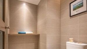 A bathroom with a toilet, a shelf with a towel, and a framed picture on the wall. - Rezen Select Hangzhou Xiaoshan Airport (Hangzhou)