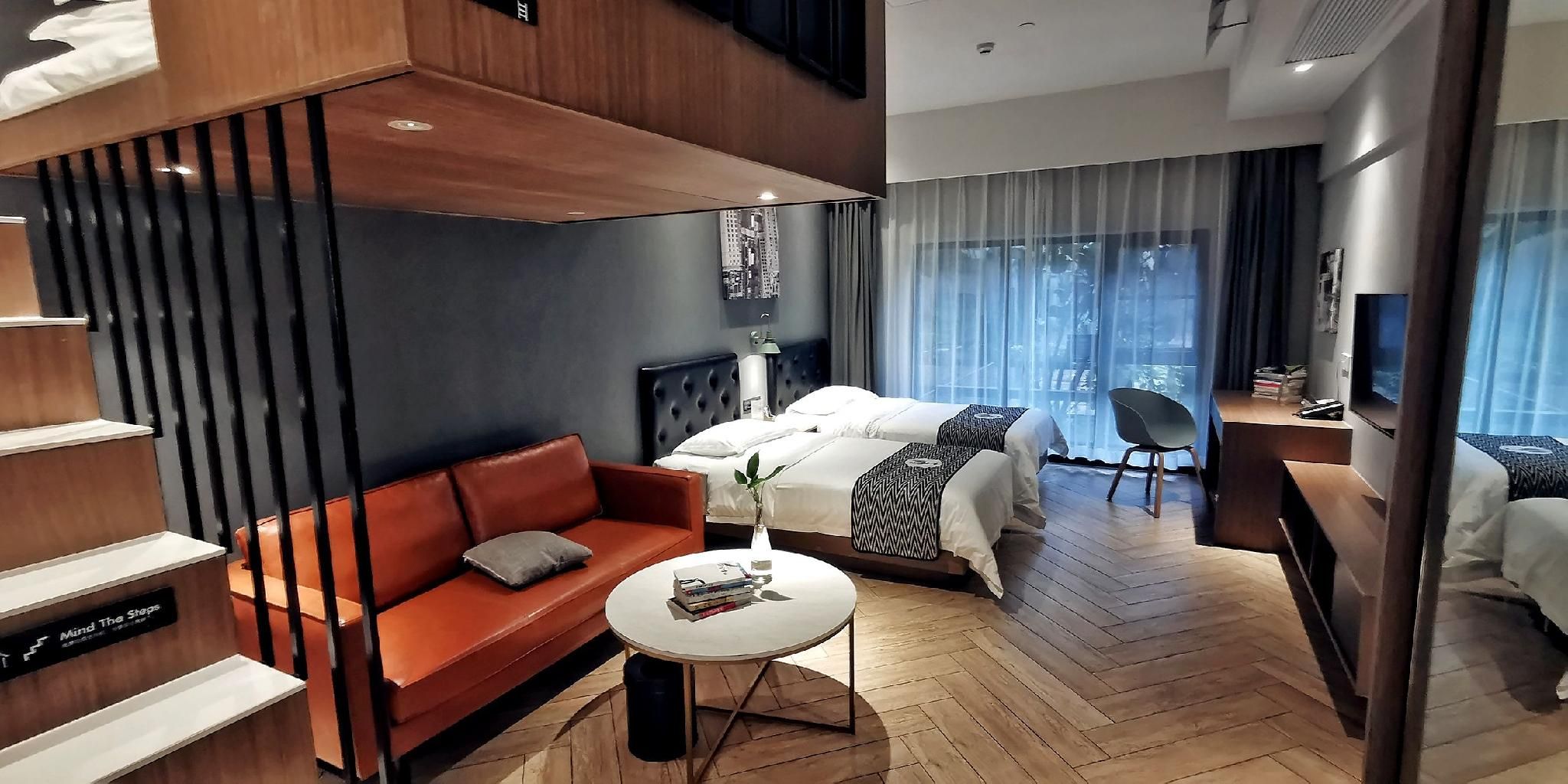 A modern hotel room with a sofa, a bed, a small table, and a chair.