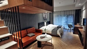 Et moderne hotelværelse med sofa, seng, lille bord og stol.