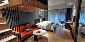 A modern hotel room with a sofa, a bed, a small table, and a chair. - Yuhuayuan Design Hotel (Haikou)