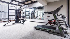Et fitnesscenter med træningsudstyr, herunder et løbebånd, styrkemaskiner og en spejlvæg.