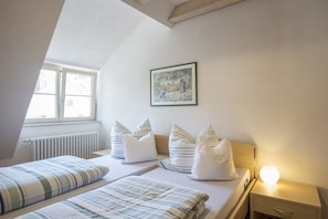 Ein Schlafzimmer mit zwei Betten, einem Heizkörper, einem Fenster und einer Nachttischlampe.