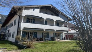Un immeuble de deux étages doté d’un balcon à l’étage supérieur, d’un porche à l’avant et d’un garage.