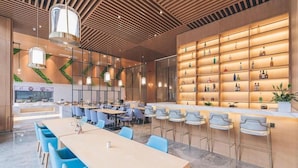A modern restaurant with a bar area, seating arrangements, and a display of bottles. - Atour Hotel (Wuxi)