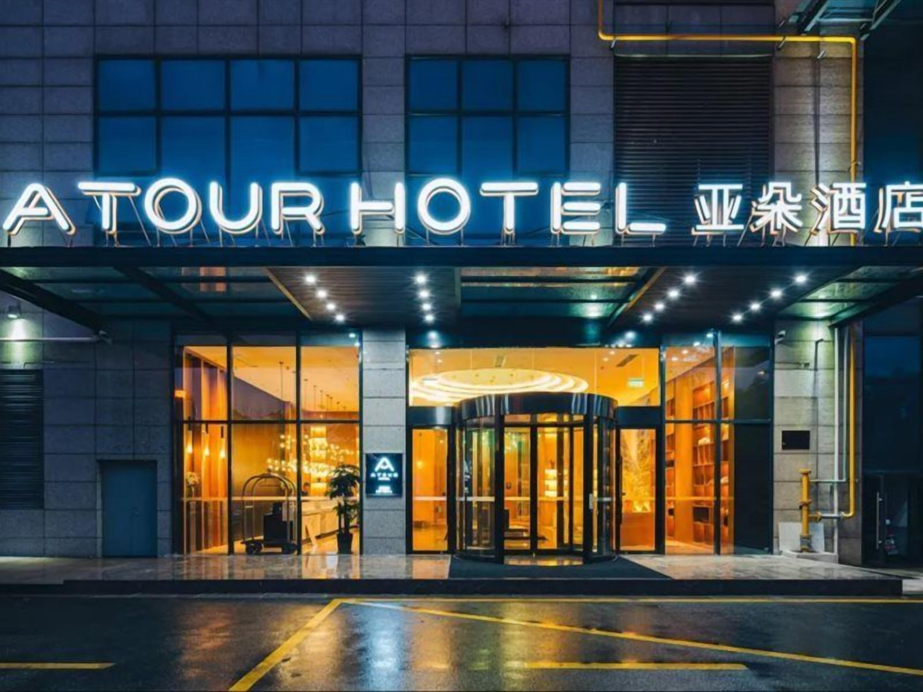 Een hotelentree met een glazen gevel, een draaideur en een bord boven de ingang.