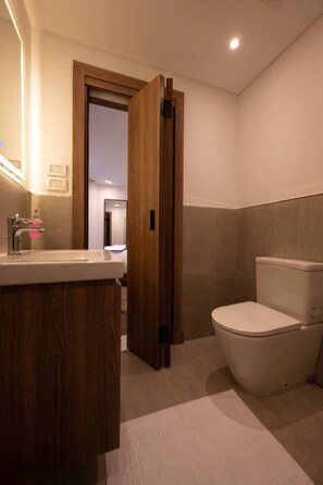 A bathroom with a wooden vanity, a toilet, and a mirror. - Lovely Home at Elevens by Spacey #7 (cairo)