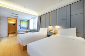 Habitación de hotel con dos camas, zona de estar, escritorio y un ventanal grande.