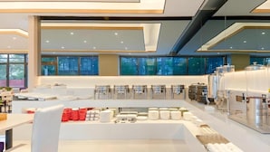 A modern breakfast area with a central serving station, seating, and a view of the city. - Lavande (Beijing)