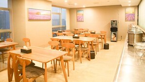 A hotel dining area with multiple tables and chairs, a buffet station, and artwork on the walls. - Greentree Inn Zhuma Railway Station Qian Plaza Branch (Zhumadian)