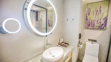 A modern bathroom with a round mirror, a white sink, and a toilet.